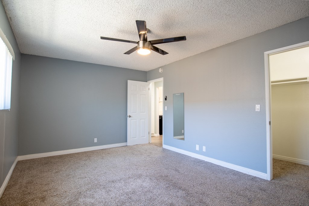 A room with a ceiling fan and carpeted floor.