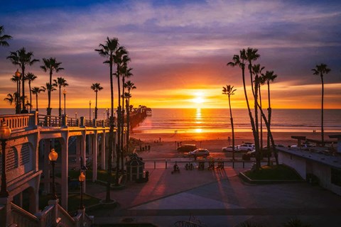 the sun sets over the beach and palm trees at the imperial beach pier