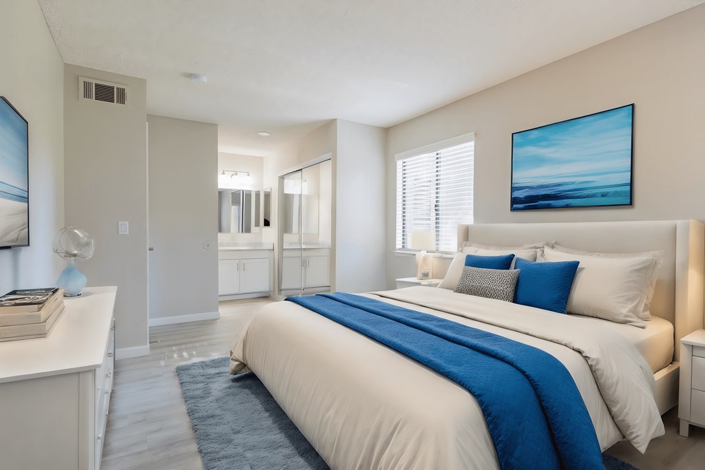 a white bedroom with a large bed and a blue blanket