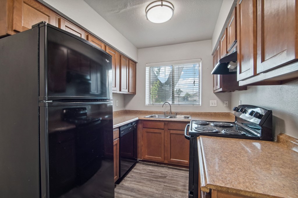 an updated kitchen with black appliances and wood cabinets