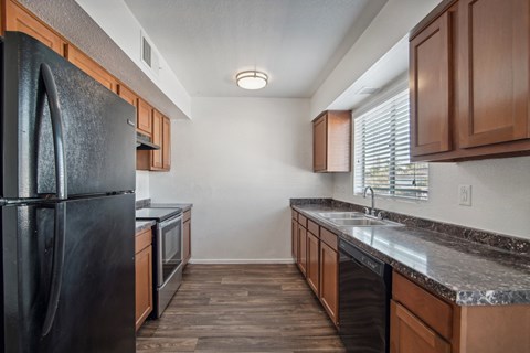 a kitchen with black appliances and wooden cabinets and granite counter tops