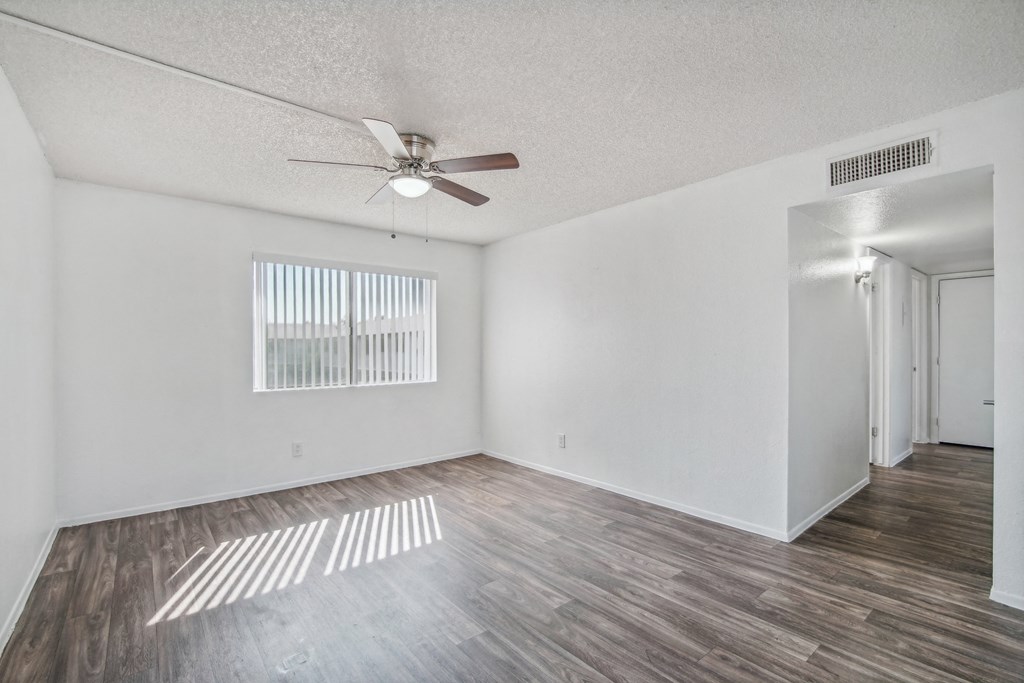 the living room of an empty apartment with a ceiling fan