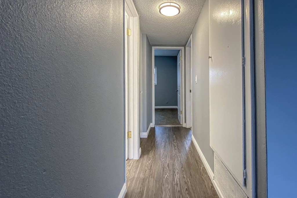 a hallway with a wood floor and blue walls and a door to a blue room
