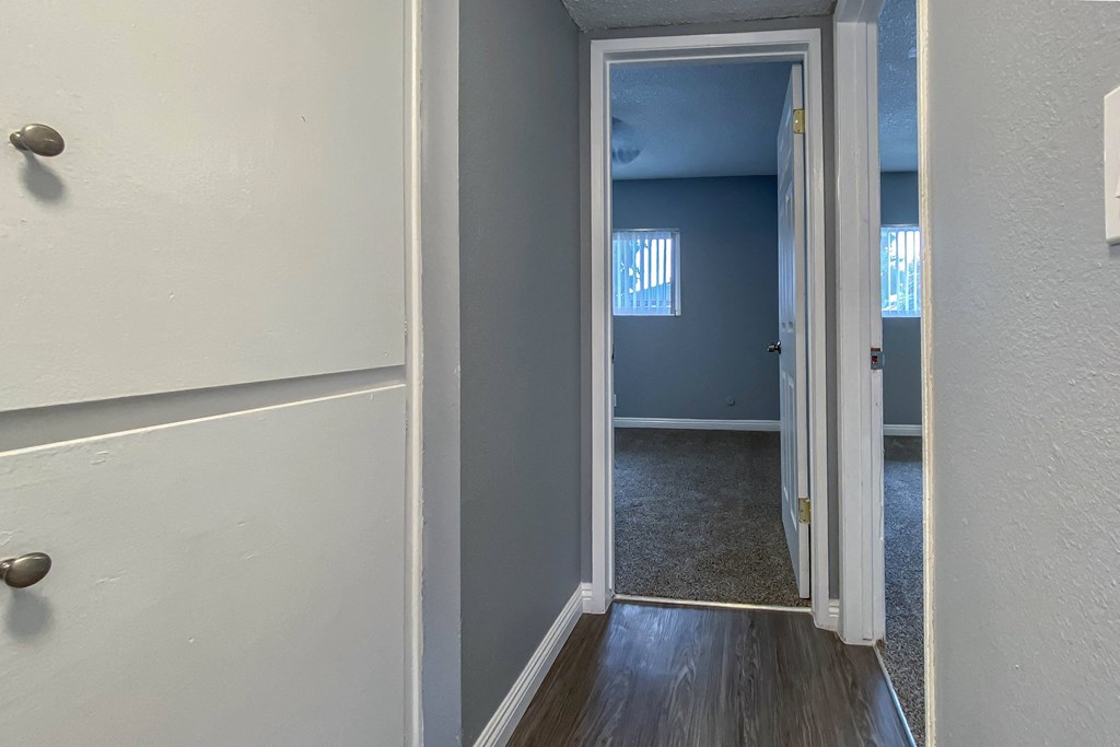 a hallway with a door to a blue room and a door into an empty room