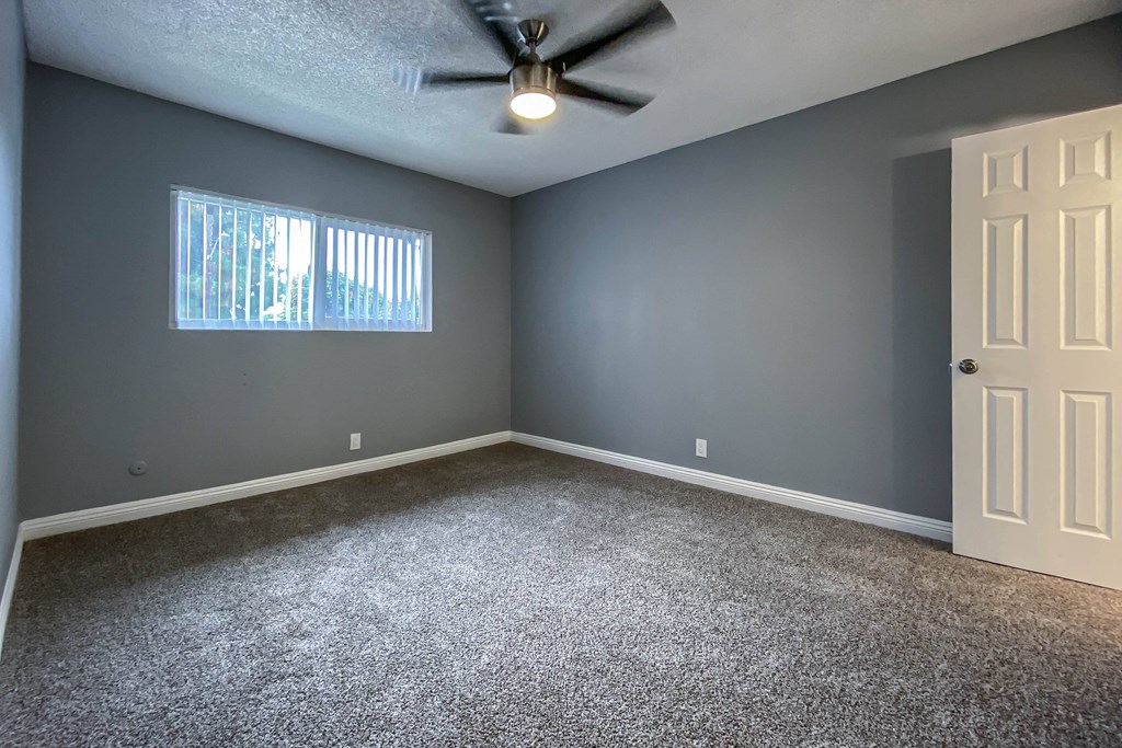 an empty room with blue walls and a ceiling fan