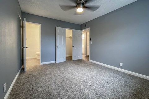an empty living room with blue walls and a ceiling fan