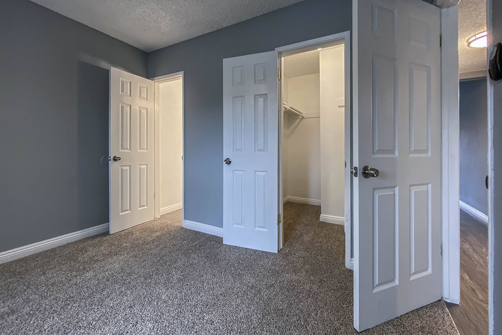 an empty room with two doors and a closet