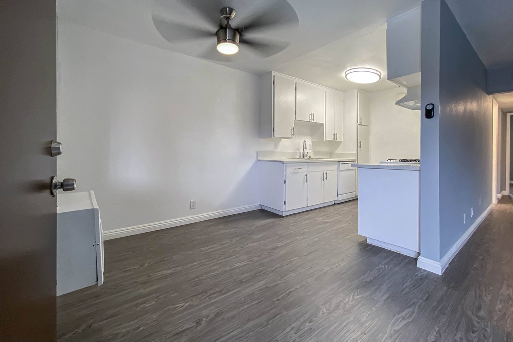 an empty kitchen with white cabinets and a ceiling fan