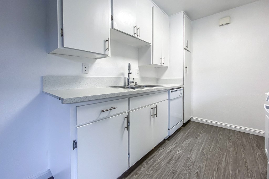A kitchen with white cabinets and a grey counter top.