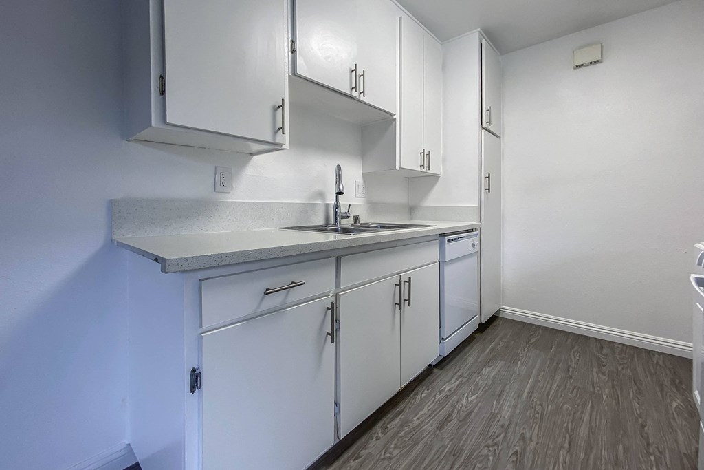 an empty kitchen with white cabinets and a sink