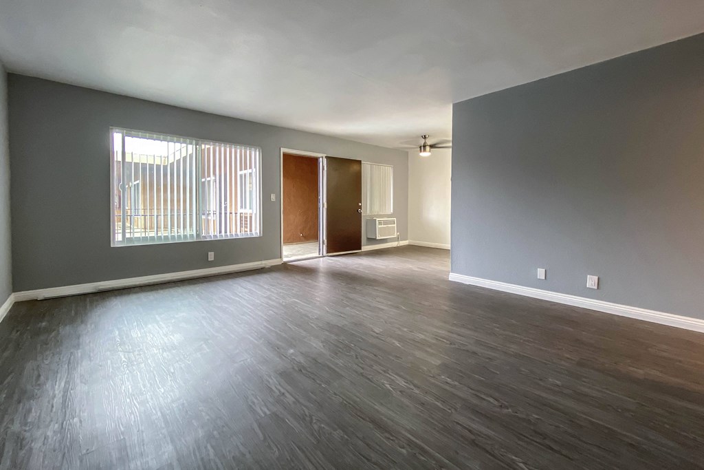 an empty living room with wood floors and grey walls