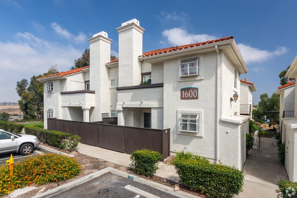 a white house with a fence and a parking lot