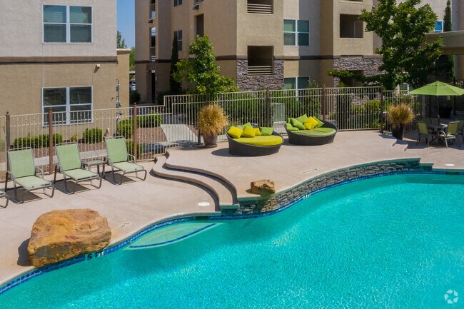 a resort style pool with lounge chairs and umbrellas