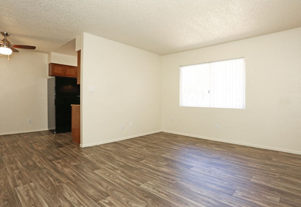 an empty living room with wood flooring and a window