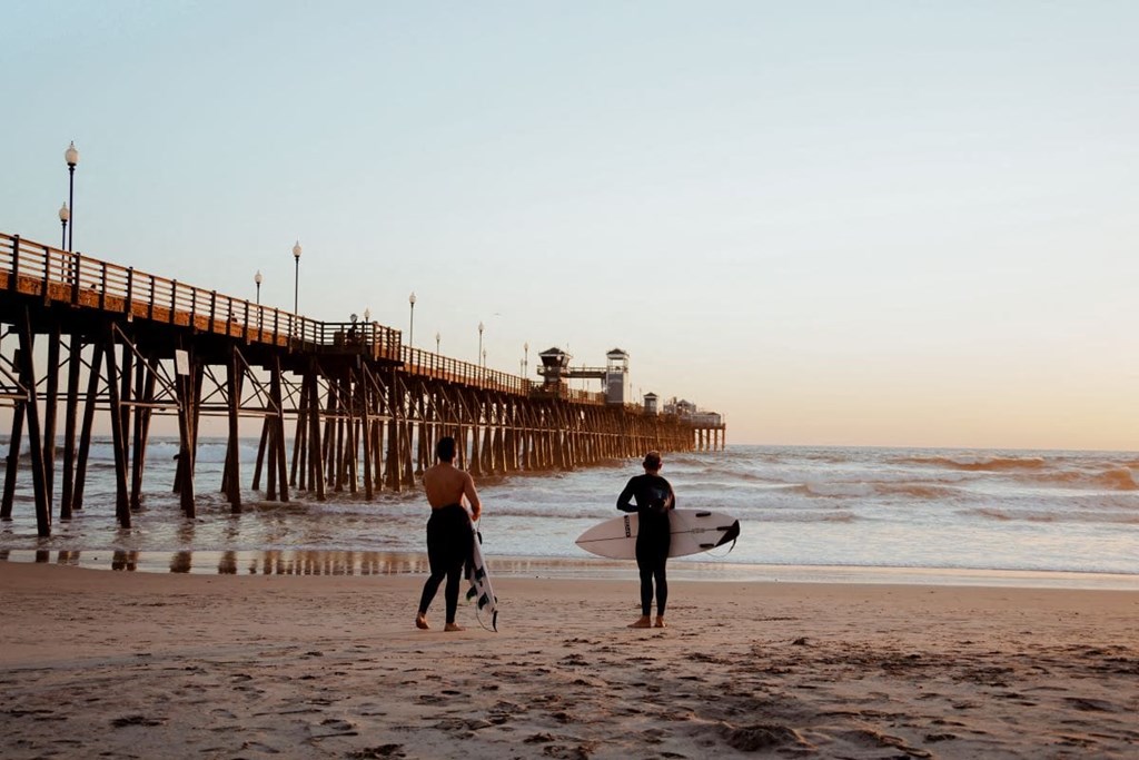two men walking on the beach with their surfboards