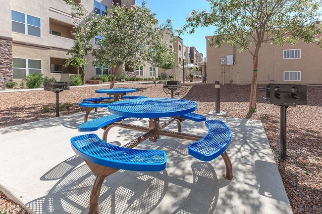 an outdoor picnic area with blue picnic tables and benches