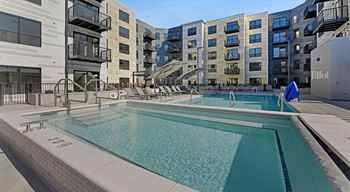 A swimming pool on a rooftop with buildings in the background.