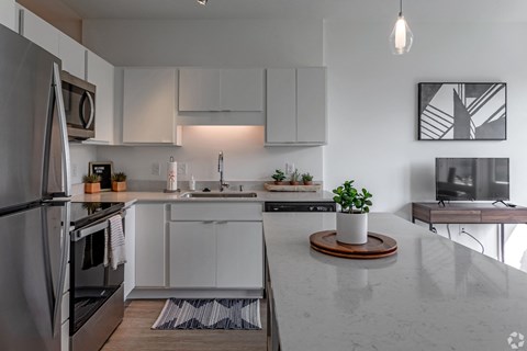 a kitchen with white cabinets and a marble counter top