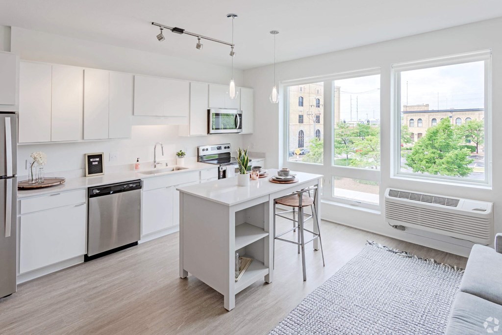 a white kitchen with an island and a large window