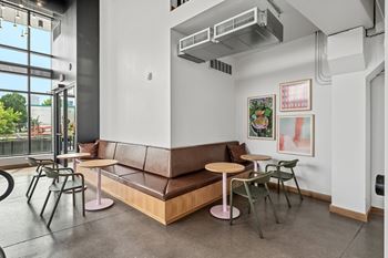 A room with a brown couch, a table, and chairs.