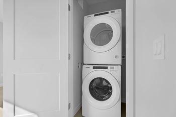 A white washing machine is stacked on top of another white washing machine in a small laundry room.