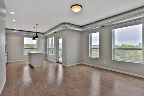 A spacious room with wooden floors and large windows.