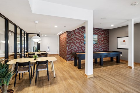 A modern dining room with a wooden floor and a red and white patterned wallpaper.