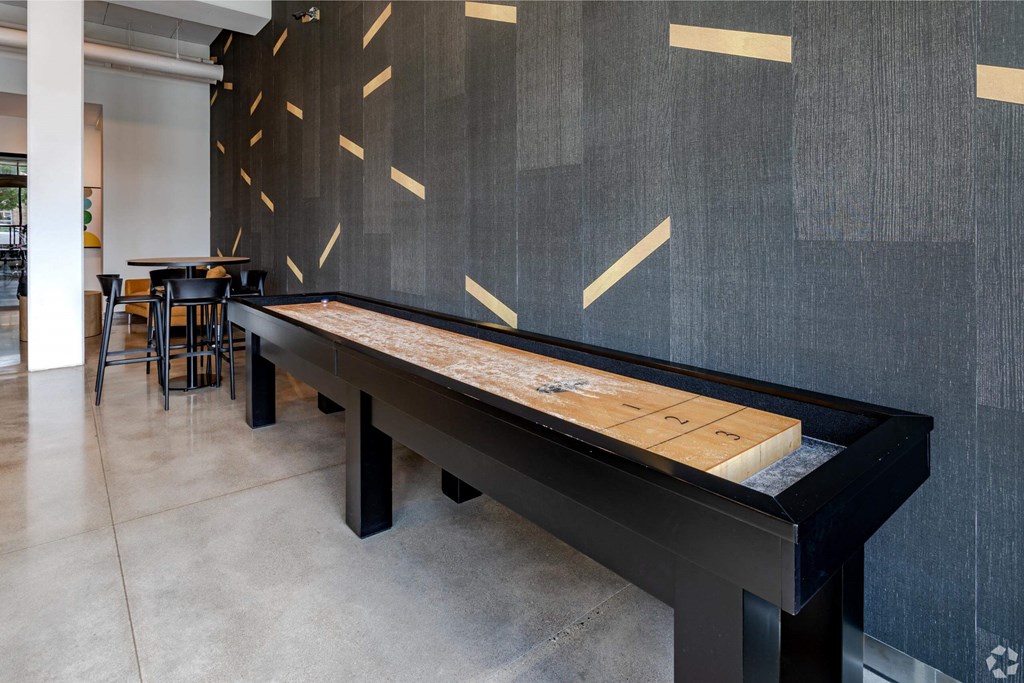 a shuffleboard table in a room with tables and chairs