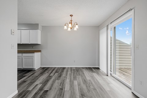 an empty living room with a sliding glass door to a kitchen