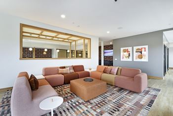 A living room with a pink couch, a white table, and a large mirror on the wall.