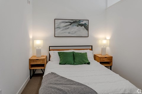 a bedroom with a bed with green pillows and a painting on the wall