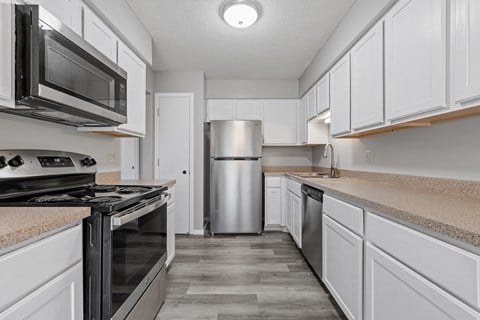 an empty kitchen with white cabinets and stainless steel appliances