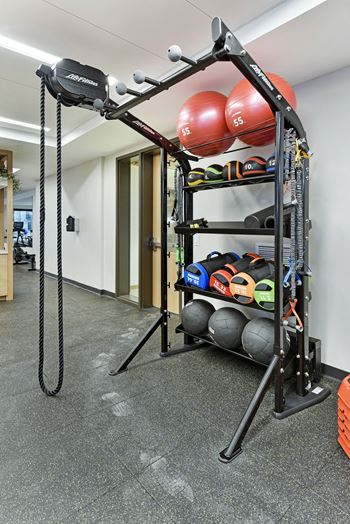 A gym with a weight rack and exercise balls.