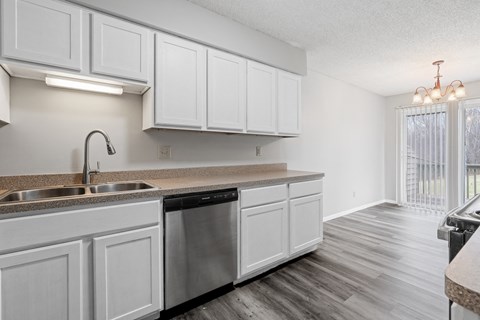 an empty kitchen with white cabinets and a stainless steel dishwasher
