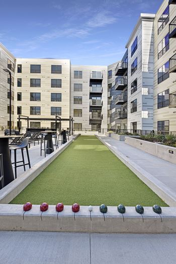 A miniature golf course is located in the courtyard of a modern apartment complex.