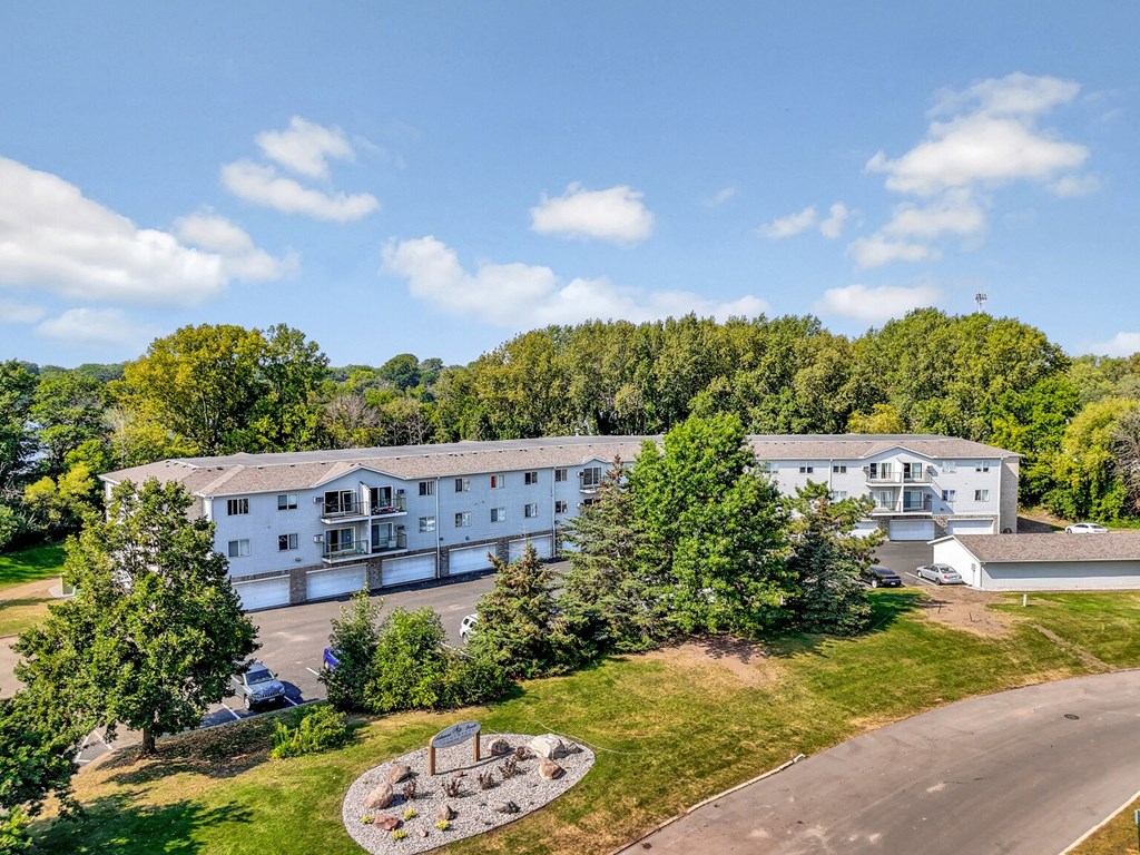 A large white building surrounded by trees and a circular garden in front.