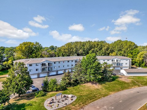 A large white building surrounded by trees and a circular garden in front.