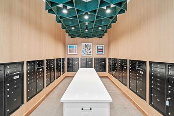 A long white table is in the middle of a room with black lockers on the walls.