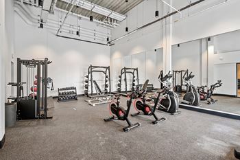 A gym with a variety of exercise equipment including treadmills, weights, and exercise bikes.