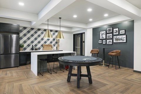 a living room with a round table and a kitchen with a refrigerator