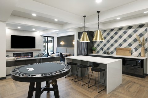 a kitchen with a round game table and a bar with stools
