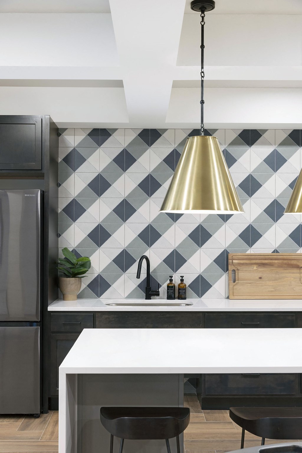 a kitchen with black and white tiles and a gold pendant light