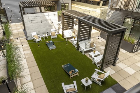 a rooftop patio with tables and chairs and a lawn