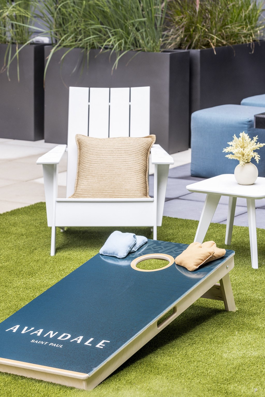 a white chair and a table with a blue rug on the grass