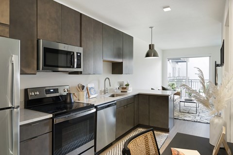 A modern kitchen with dark brown cabinets and stainless steel appliances.