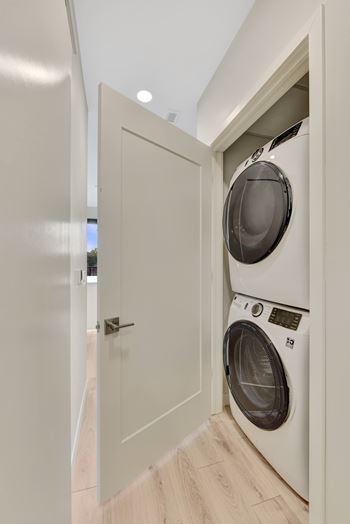 A white door opens to a laundry room with a washer and dryer.