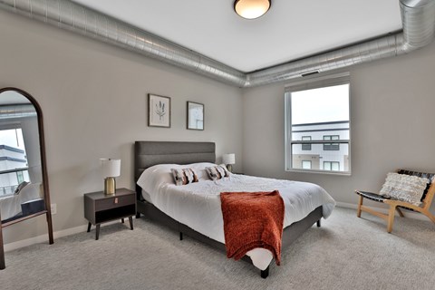 A bedroom with a large bed and a window overlooking a cityscape.