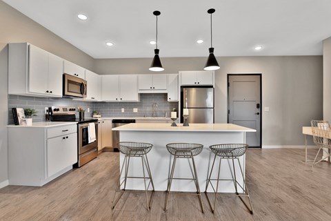 A modern kitchen with a center island and bar stools.