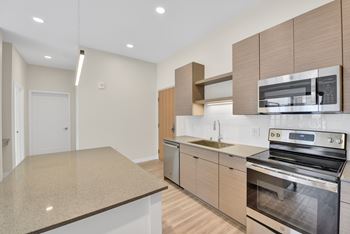A modern kitchen with a granite countertop and stainless steel appliances.