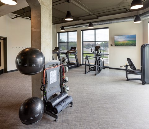 A gym with a variety of equipment including a treadmill, a stationary bike, and a weight bench.